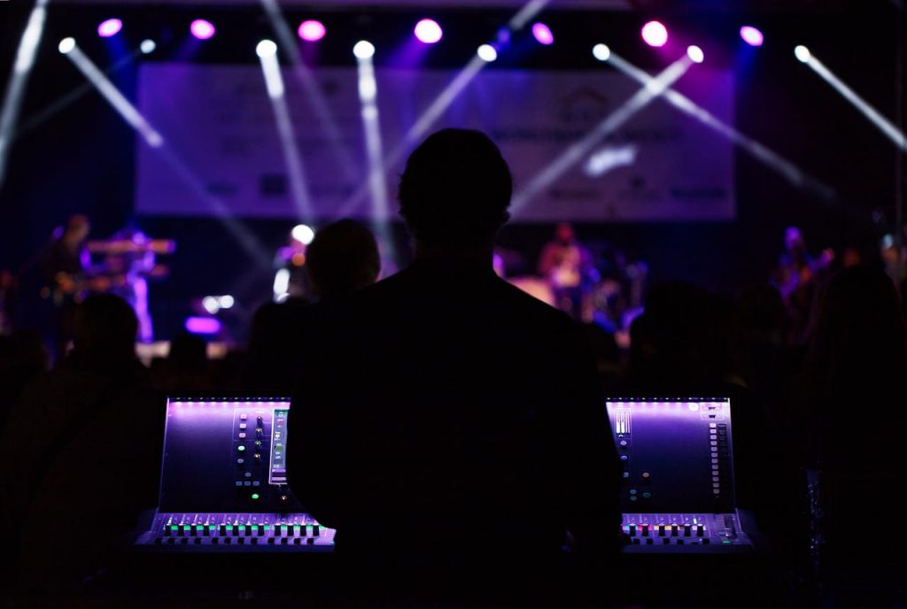 pexels-photo-2952834 A sound engineer manages the audio mixer during a vibrant live concert with colorful lighting.